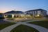 Elegant apartment complex at dusk featuring modern architecture, lush landscaping, and a welcoming clubhouse entrance.