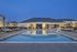Luxurious apartment complex with an illuminated pool area at dusk, featuring modern lounge chairs and a stylish clubhouse.