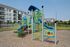 Vibrant community playground with colorful slides and climbing structures, surrounded by modern apartment buildings and lush green spaces.