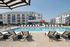 Luxurious apartment complex with modern architecture featuring a pristine swimming pool surrounded by stylish lounge chairs, perfect for relaxation.