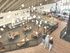 Modern open community space with bright lighting, communal tables, and stylish seating areas.
