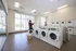 Bright and modern laundry room with natural light, featuring multiple front-load washers and dryers, creating a convenient and inviting space.