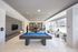 Luxurious apartment lounge with modern marble decor, featuring a pool table, table tennis, and elegant seating with large panoramic windows.