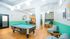 Vibrant recreational room featuring a modern pool table, stylish seating areas, and a cozy dining nook with eclectic decor.