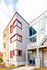 Modern apartment building with sleek architectural design, featuring large glass windows and bold red accents.