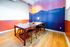 Vibrant meeting space with a modern wooden table, artistic mountain mural, and warm lighting.