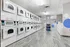 Modern apartment laundry room with stylish tile flooring and rows of efficient washing and drying machines.