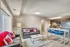 Modern open-concept living room with chic seating and bright red accents, seamless transition to a stylish kitchen with stainless steel appliances.