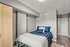 Cozy bedroom with modern design featuring a comfortable bed, stylish blue bedding, and sleek wooden flooring.