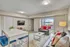 Bright and modern living room featuring plush seating with vibrant red accents, a sleek white dining table, and a large window offering natural light and a scenic view.