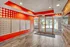 Vibrant apartment lobby with modern decor, featuring sleek mailboxes on a bold red polka dot wall and spacious glass entry doors.
