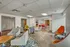 Modern communal lounge with a vibrant mix of seating options, featuring sleek gray and orange chairs and dynamic red tables, perfect for socializing or relaxing.
