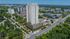 Stunning aerial view of a modern high-rise apartment building surrounded by lush greenery, in an urban setting with convenient access to amenities.