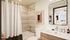 Elegant bathroom featuring modern fixtures, a stylish art piece, and a large mirror reflecting natural light.