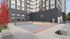 Modern apartment complex featuring a vibrant outdoor sports court with basketball and tennis areas, surrounded by sleek architecture and lush greenery.