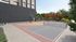 Modern outdoor sports court with basketball hoop and ample seating surrounded by lush greenery.