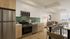 Modern apartment kitchen and dining area with sleek stainless steel appliances, stylish backsplash, and cozy living corner.