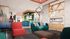 Vibrant and modern lounge area featuring colorful seating, a sleek fireplace, and an entertainment zone with a basketball game.