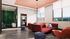 Chic modern living room with vibrant red sofas, stylish armchairs, and a panoramic city view through large windows.