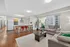 Contemporary open-plan living area with chic kitchen, stylish bar stools, and cozy seating, overlooking cityscape.