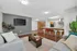 Modern open-concept living room with sleek kitchen, featuring stylish bar stools and cozy seating area, perfect for entertaining.