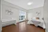 Bright and spacious bedroom with large windows, elegant wooden flooring, modern decor, and a cozy bed, offering a serene ambiance and natural light.