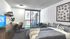 Modern bedroom featuring a cozy bed with stylish pillows, a sleek desk with a chair, and a balcony view through floor-to-ceiling glass doors.