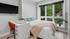 Bright bedroom with large windows, cozy bed with pastel pillows, and a sleek desk with modern decor.
