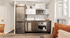 Modern kitchen with stainless steel appliances, white cabinets, and cozy seating area bathed in natural light.