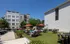 Charming outdoor seating area with red umbrellas and modern apartment buildings in the background, perfect for relaxation and social gatherings.