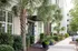 Charming apartment exterior with lush landscaping, featuring palm trees and vibrant greenery for a welcoming entrance.