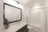 Modern and elegant bathroom featuring a sleek vanity with a large mirror, stylish lighting, and a pristine tub with a shower curtain.