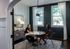 Elegant home office space with dark paneled walls and natural light, featuring a round table and comfortable seating, ideal for productivity and meetings.
