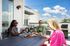 Chic rooftop terrace with three friends enjoying wine and a cheese platter under a clear blue sky.
