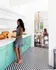 Hosting kitchen with stylish mint green cabinets and classic checkered floor, leading to a sunlit dining area with elegant chandelier.