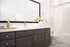Bright and modern bathroom featuring sleek dark cabinetry, a chic white countertop, and elegant decor with a large mirror.