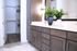 Elegant bathroom with sleek dark wood cabinetry, a modern vanity, and vibrant greenery adding a touch of nature, complemented by a plush white rug and spacious walk-in closet.