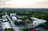 Aerial view of modern apartment residences surrounded by lush greenery and cityscape, offering urban living with a touch of tranquility.