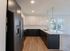 Modern kitchen with sleek black and white cabinetry, stainless steel appliances, and elegant pendant lighting.