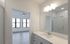 Bright and modern bathroom with sleek fixtures, leading to a spacious room with large windows and stylish flooring.