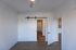 Inviting room with sleek barn door, elegant hardwood flooring, and a glimpse into a modern kitchen with ambient lighting.