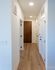 Bright hallway featuring elegant wood flooring, modern white doors, and minimalist wall tones, exuding a welcoming ambiance.