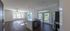 Bright, modern open-concept kitchen and living area with elegant dark wood flooring, large windows for natural light, and sleek stainless steel appliances.