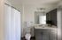 Modern bathroom oasis with sleek gray cabinetry, large mirror, and elegant decor, featuring a crisp white shower curtain and natural light.