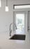 Sleek and modern kitchen island with a polished chrome faucet and natural light streaming through stylish blinds in a bright apartment.