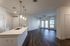 Modern open-plan living area featuring sleek wood floors, a stylish kitchen island with pendant lighting, and large windows for abundant natural light.