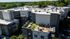 Modern apartment complex with spacious rooftop terrace featuring stylish outdoor seating and lush greenery, surrounded by scenic views.