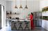 Modern kitchen with sleek stainless steel appliances, elegant pendant lighting, and stylish bar stools at a marble island, enhanced by natural light and greenery accents.