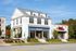 Charming white building featuring cozy bakeshop and steamers' eatery, nestled on a sunny street with vibrant greenery.