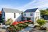 Charming two-story buildings with outdoor seating area featuring vibrant red umbrellas, surrounded by lush greenery and a clear blue sky.